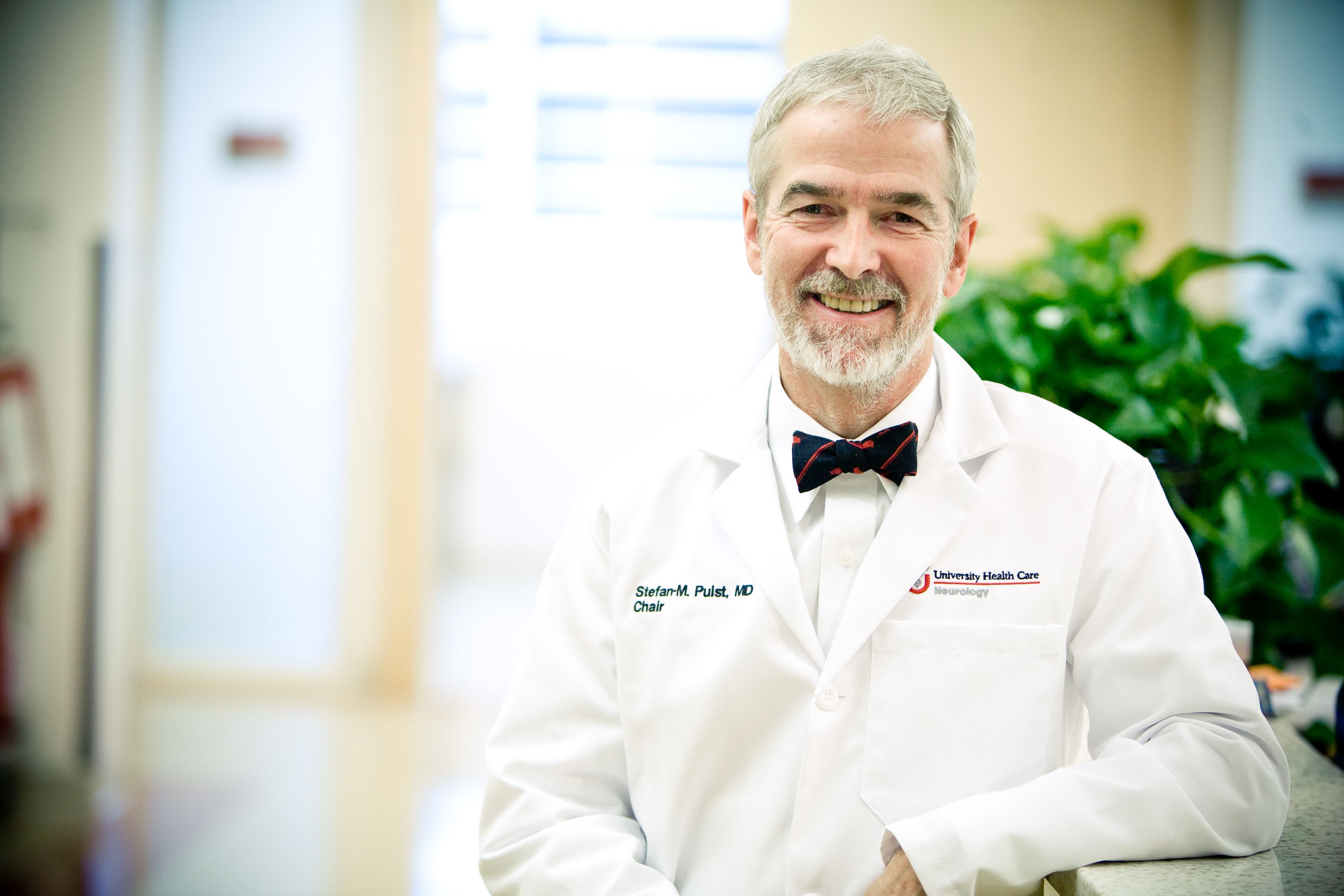 Waist-up image of Dr. Pulst in a white lab coat, smiling at the camera.